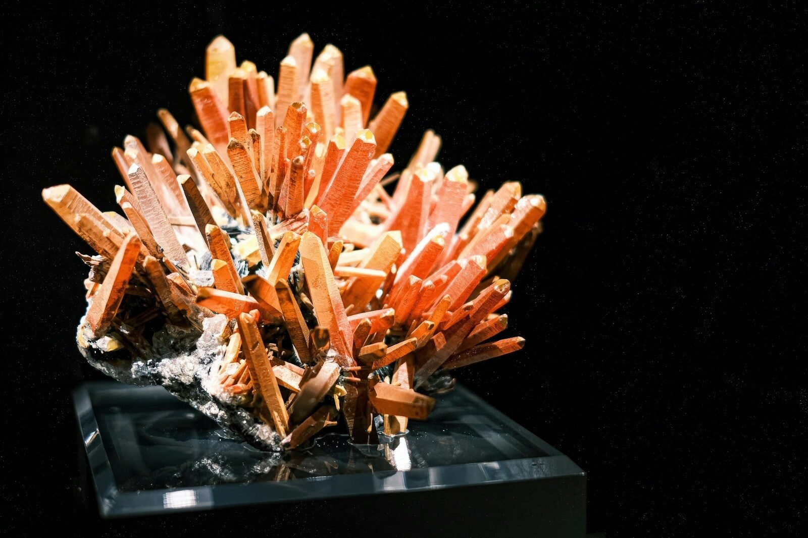 Cluster of orange quartz crystals on black background